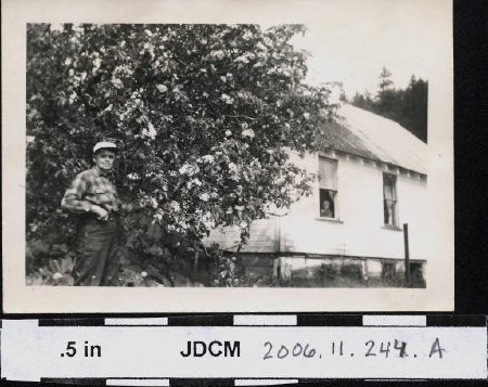 Erma Olson in front of old apple tree; Marie Peterson in window
