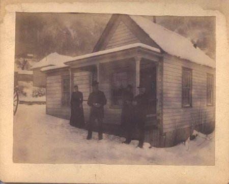 four people in front of house