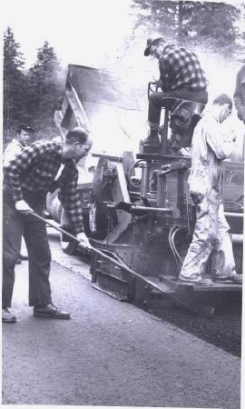 4 men working on asphalt paver